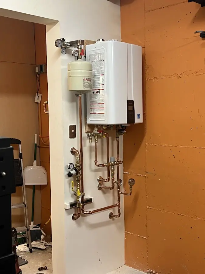 Plumbing technician inspecting water heater connections in Penbrook